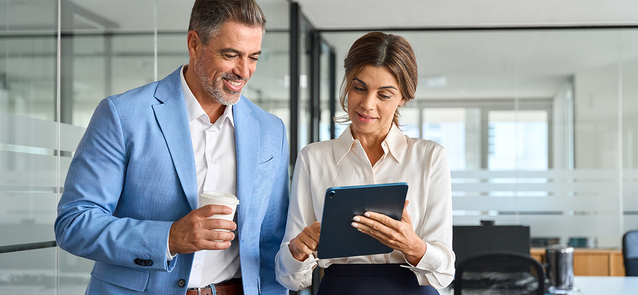 Kobieta i mężczyzna w biurze omawiający dane na tablecie.